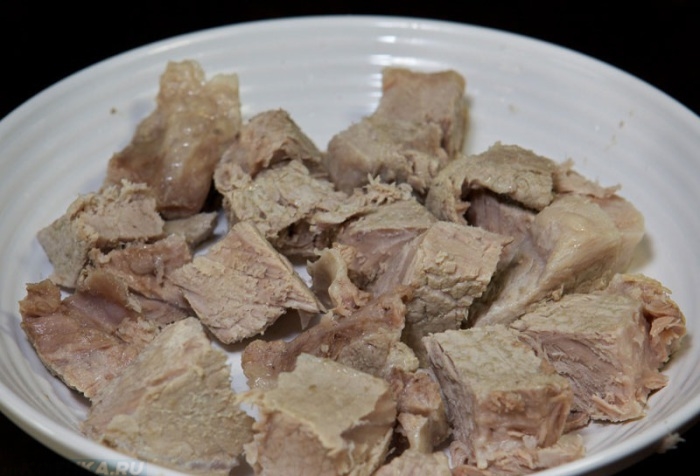 Отварное мясо кусочками на белой тарелке